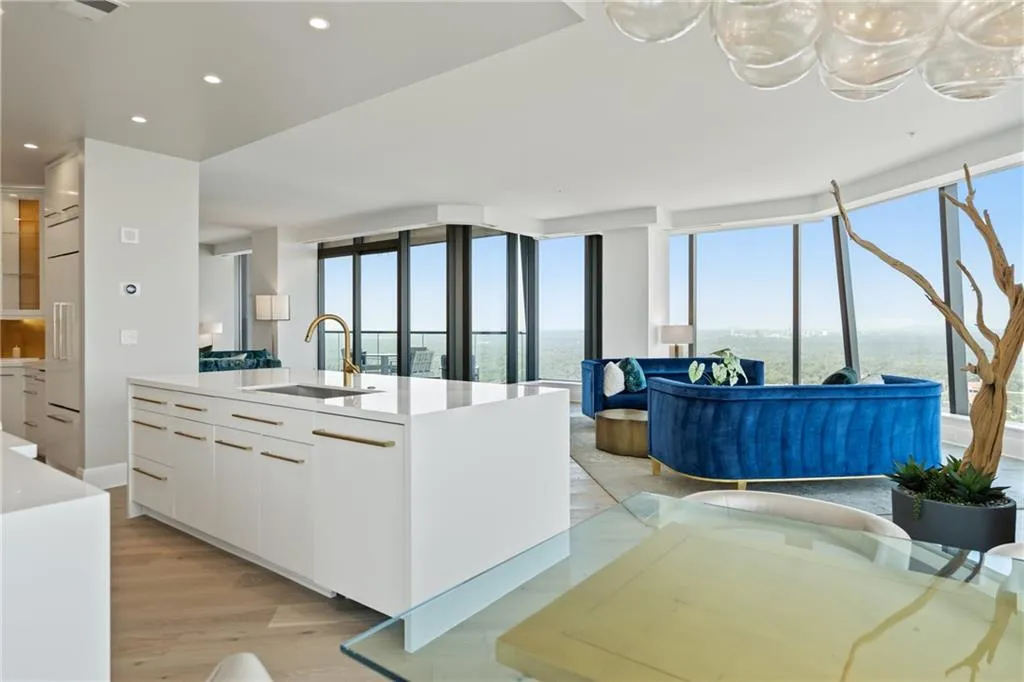 Kitchen featuring modern cabinets, white cabinetry, open floor plan, light stone counters, and floor to ceiling windows