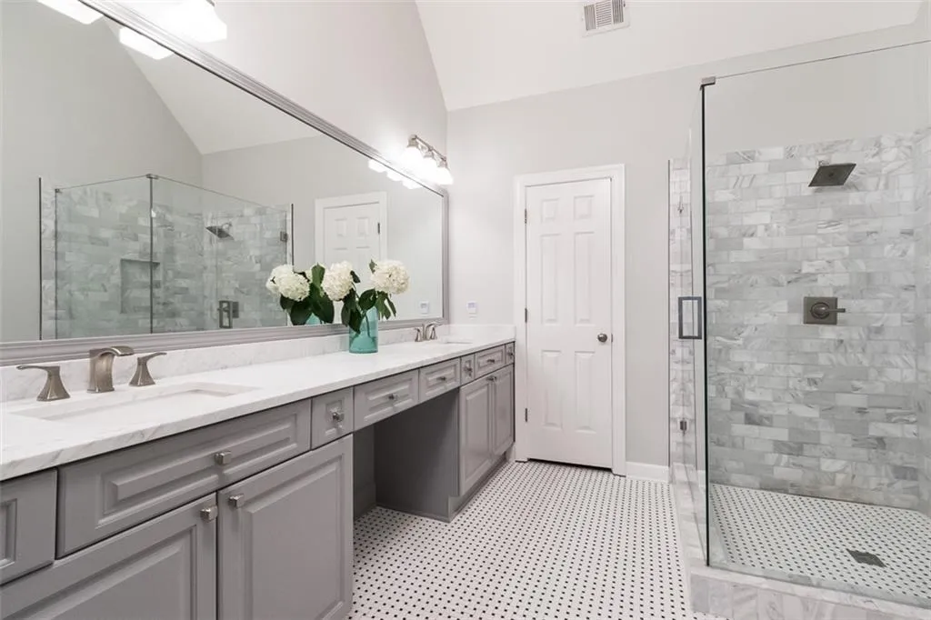 Renovated master bath features a vaulted ceiling, marble counter and frame-less shower.