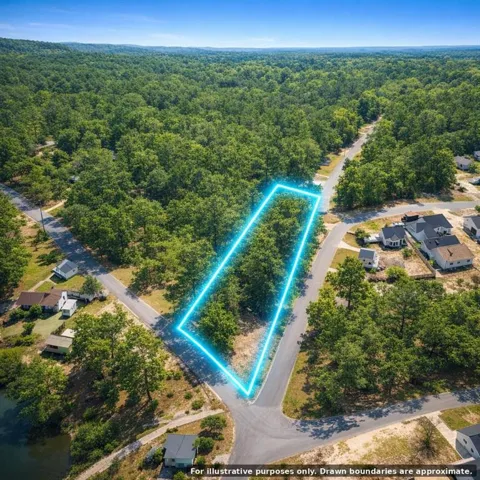 Wooded parcel with paved road frontage, surrounded by mature trees, situated within a developing community