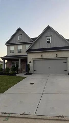 Two-story residence featuring a gray garage door, brick and shingle siding, and a concrete driveway