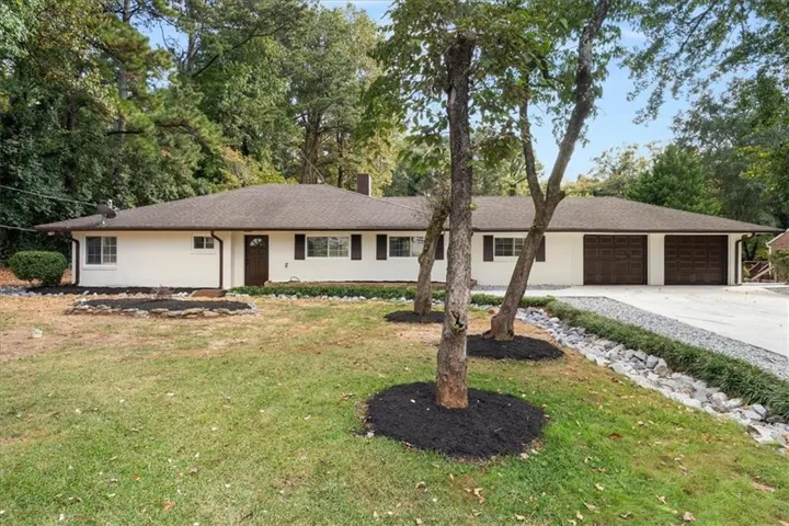 Single-story residence featuring a two-car garage with wood-finish doors, a concrete driveway, and a shingle roof