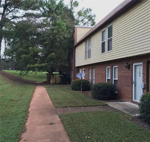 View of property exterior featuring a lawn and brick siding