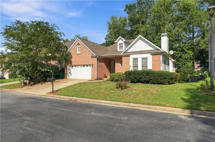 Brick and siding exterior with a two-car garage, mature front yard landscaping, and a dormer window