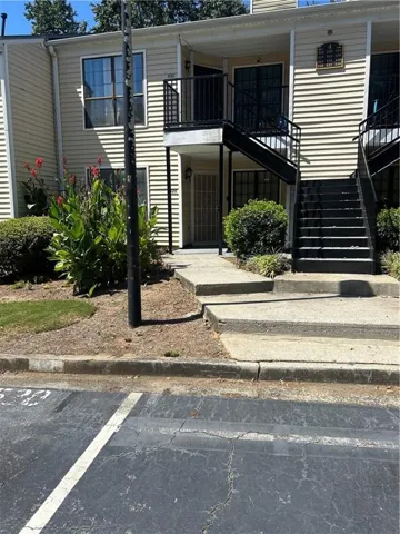 Two-story building with horizontal siding, featuring multiple entry points and an exterior staircase with metal railings