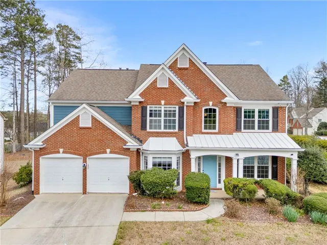 Traditional home featuring brick siding, concrete driveway, and roof with shingles