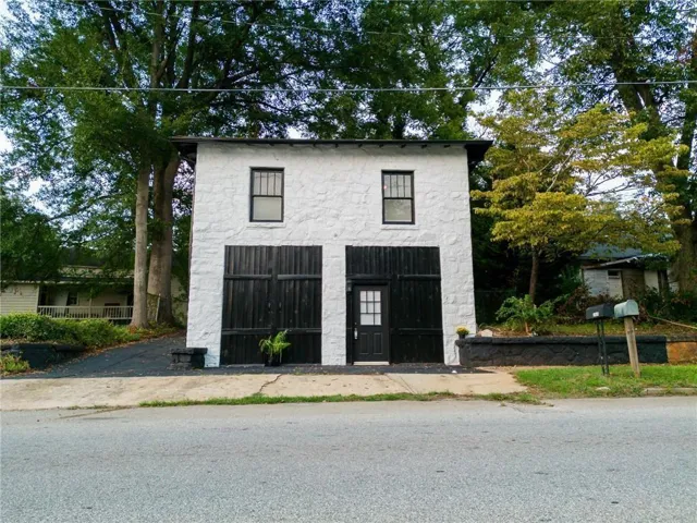 Two-story exterior with white textured facade, black trim windows, and two large black doors