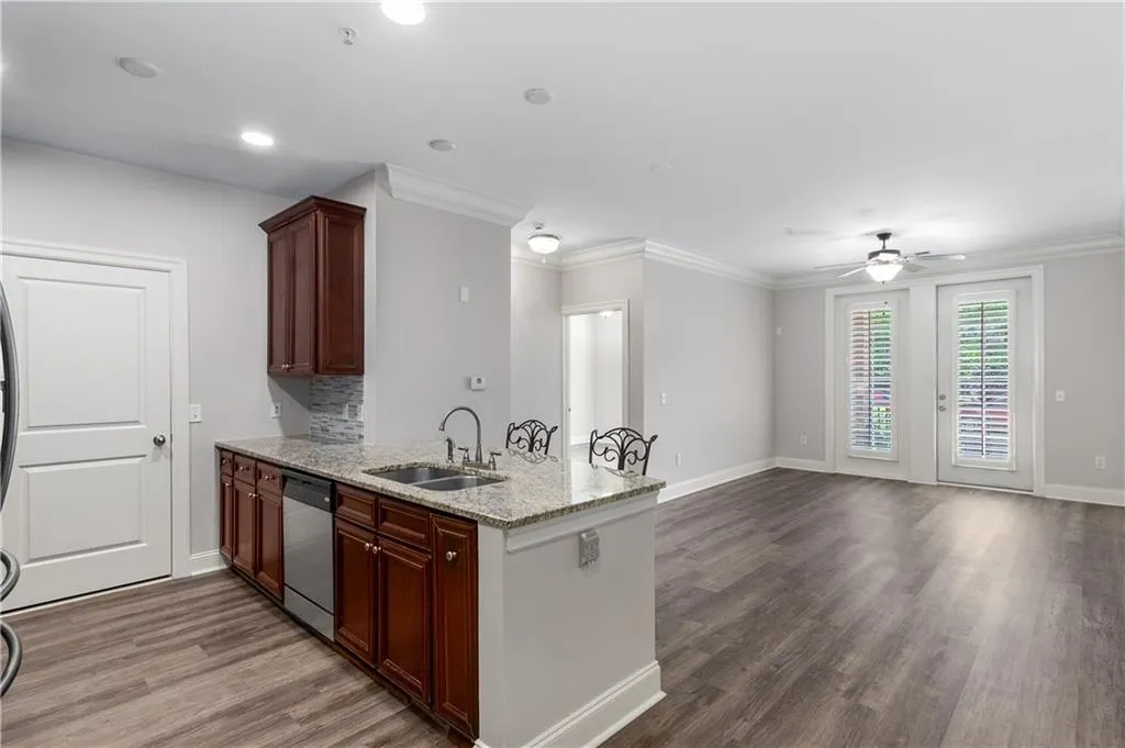 Kitchen with light stone counters, a peninsula, dark wood finished floors, tasteful backsplash, and a ceiling fan