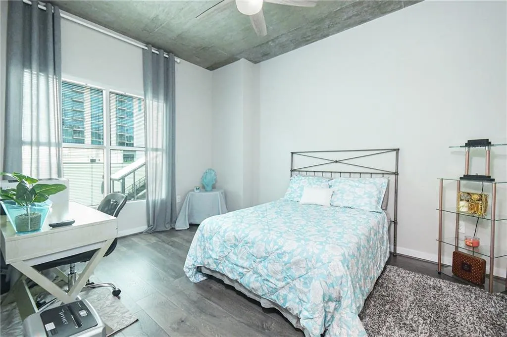 Bedroom with wood finished floors, an office area, and ceiling fan