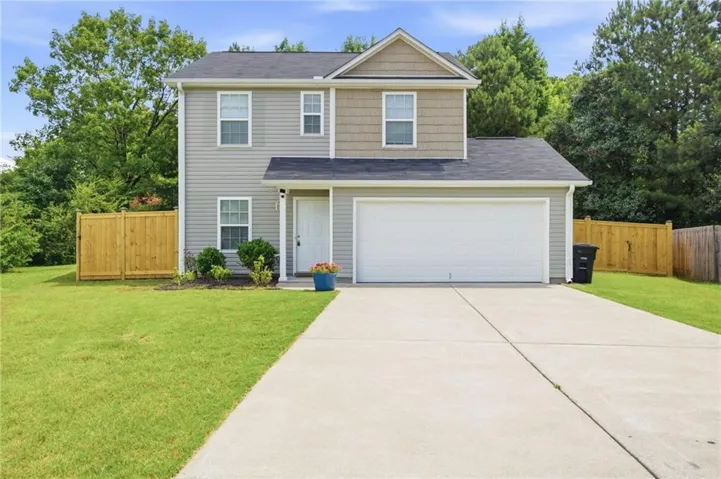 Two-story residence featuring light gray siding, a prominent two-car garage, and a concrete driveway