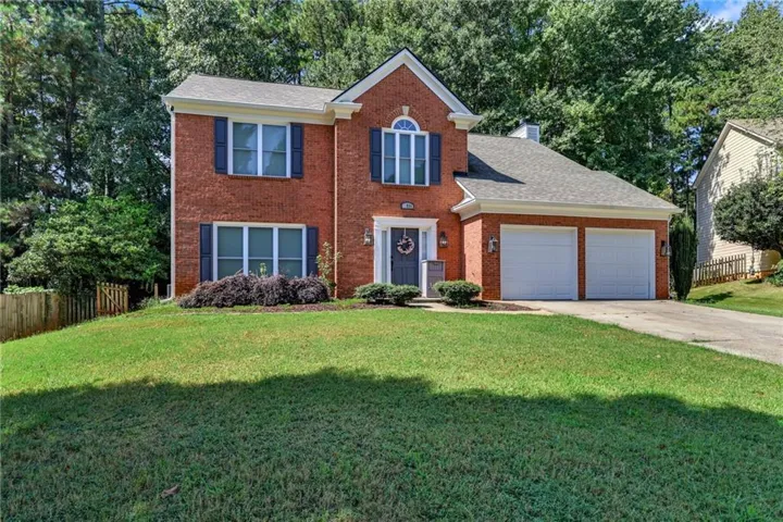 Brick exterior with dark shutters, arched window, and attached two-car garage