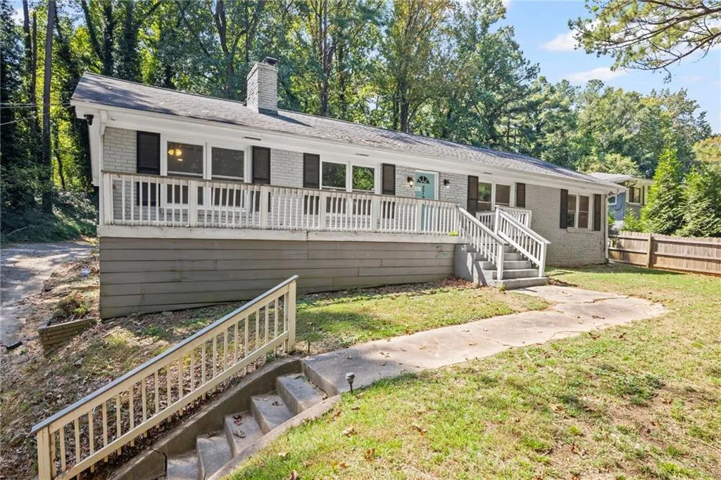 Ranch-style home with stairs, a chimney, view of scattered trees, a front yard, and brick siding