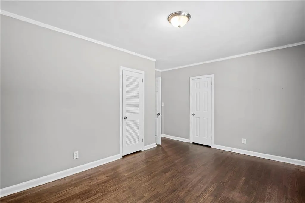 Empty room featuring ornamental molding and dark wood-style flooring