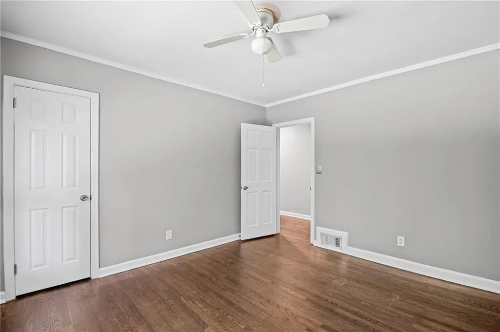 Unfurnished bedroom with ornamental molding, dark wood-style flooring, and ceiling fan