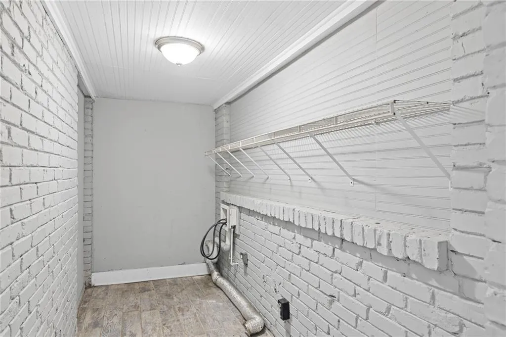 Washroom with brick wall and hookup for a washing machine