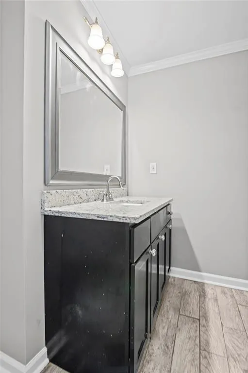 Bathroom with light wood-style flooring, crown molding, and vanity
