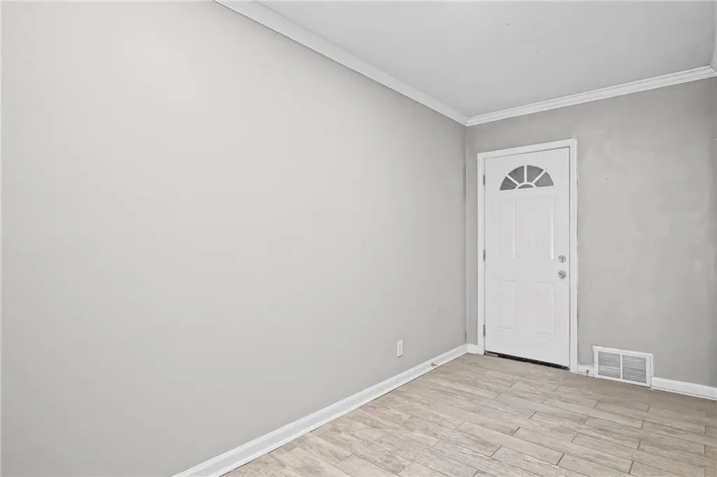 Foyer entrance featuring crown molding and light wood-style flooring