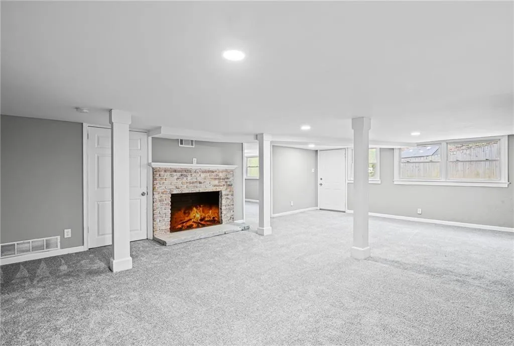 Basement featuring a brick fireplace, carpet flooring, and recessed lighting