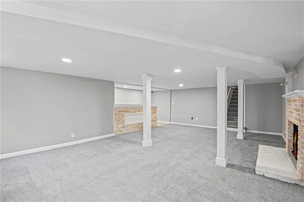 Finished basement with a fireplace, light carpet, and recessed lighting