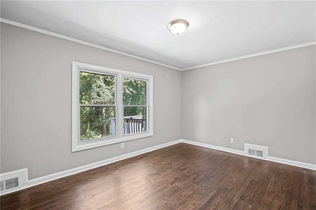 Spare room with crown molding and dark wood finished floors