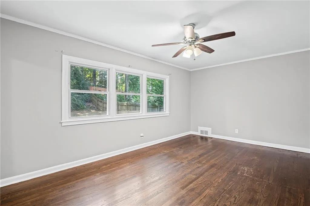 Spare room with crown molding, dark wood finished floors, and ceiling fan
