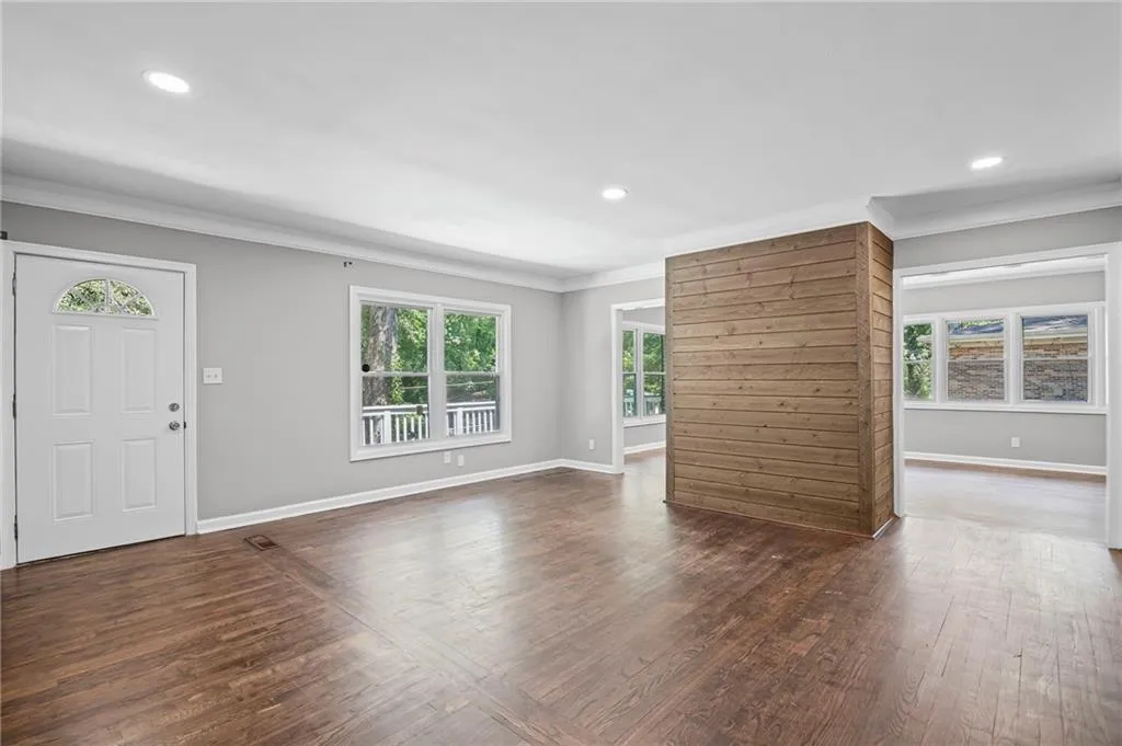 Unfurnished living room featuring ornamental molding, dark wood-type flooring, and recessed lighting