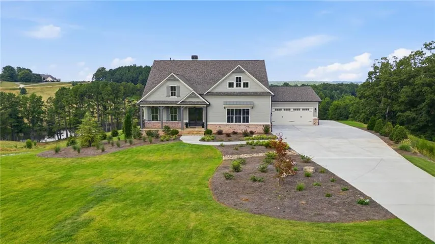 Craftsman-style home with an attached three-car garage, expansive concrete driveway, and front landscaping