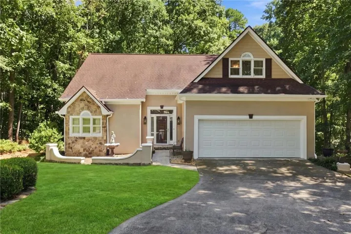 Stucco exterior with stone accents, an attached two-car garage, and a gabled roofline
