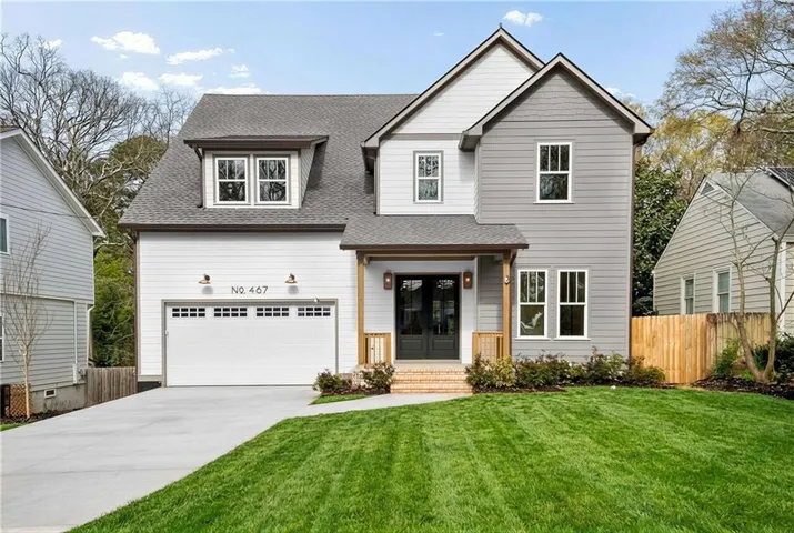 View of front facade featuring a shingled roof, french doors, driveway, and an attached garage