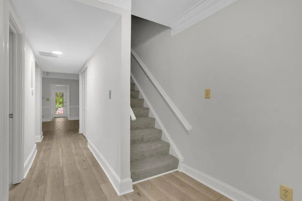 Staircase with light hardwood / wood-style flooring and ornamental molding
