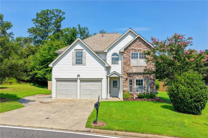 Two-story residence featuring a stone and siding exterior, an arched window accent, and an attached two-car garage