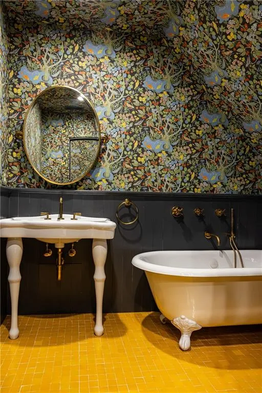 Charming ensuite bath pairs dramatic wallpaper with a classic clawfoot tub and elegant vanity.