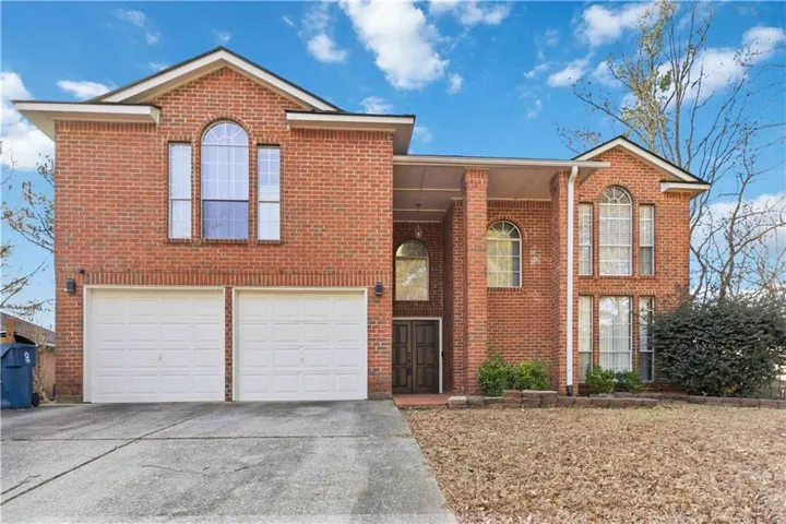Traditional-style home featuring an attached garage, driveway, brick siding, and covered porch