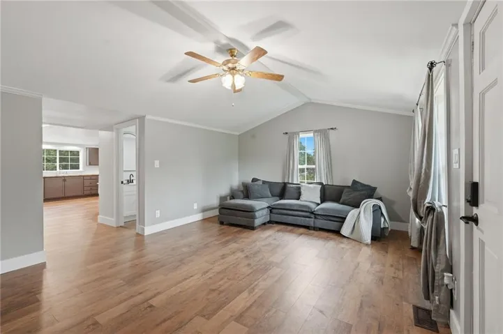 Living area featuring wood-finish flooring, vaulted ceilings, and a ceiling fan