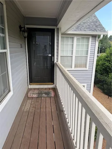 Covered entryway featuring wood-finish flooring, protective railing, wall-mounted lighting, and a screen door