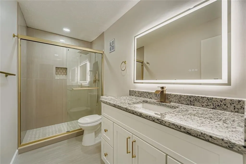 Full bath featuring vanity, a shower stall, a textured ceiling, and recessed lighting