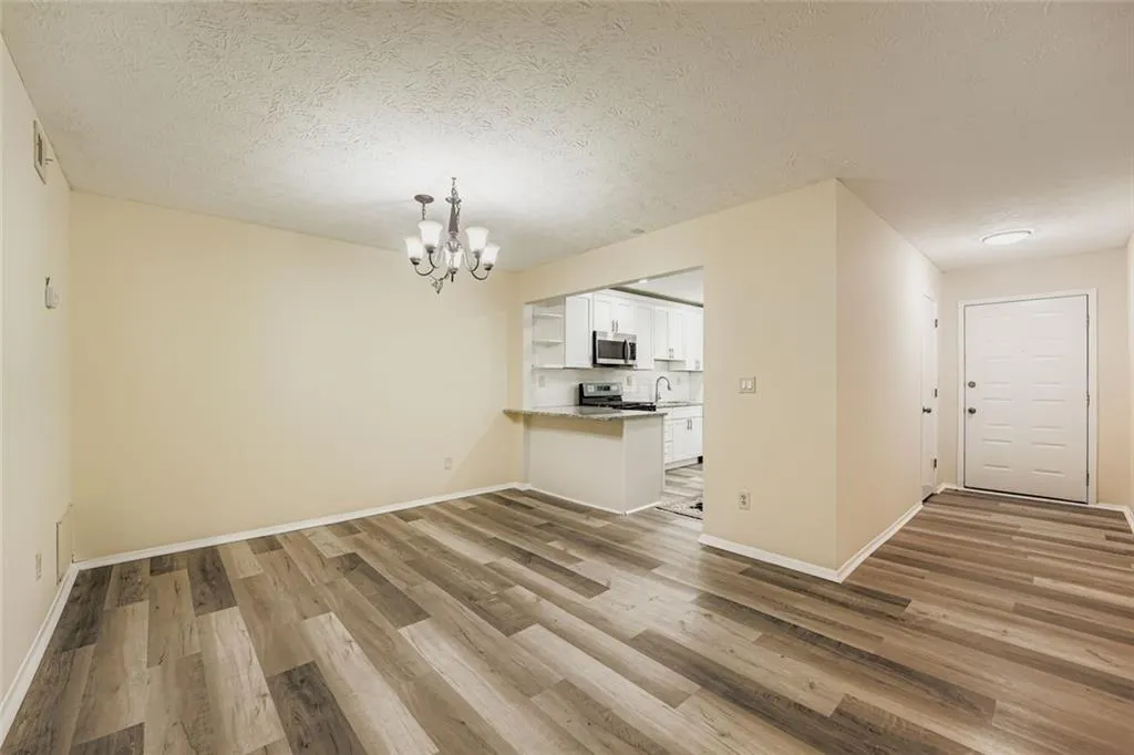 Unfurnished dining area featuring light wood-type flooring, a chandelier, and a textured ceiling