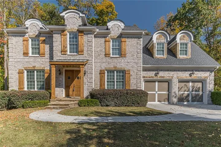 French country inspired facade with a front lawn, driveway, a garage, and brick siding