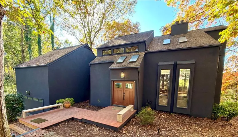 Back of property with a deck, a chimney, roof with shingles, and stucco siding