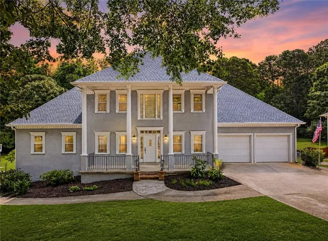 Stucco exterior with a columned porch, multiple dormer windows, and a two-car garage