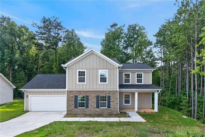 Two-story residence featuring a brick and siding facade, an attached garage, a concrete driveway, a covered front entry, and a contrasting dark roof