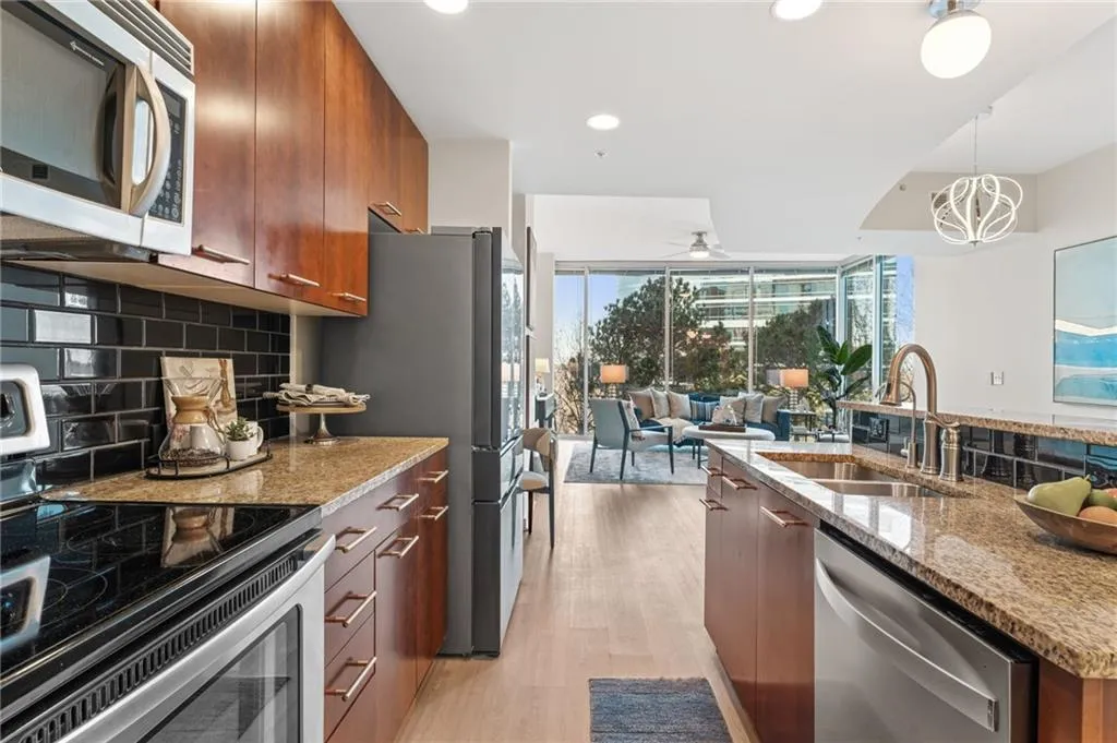 Kitchen with light stone counters, stainless steel appliances, modern cabinets, pendant lighting, and decorative backsplash