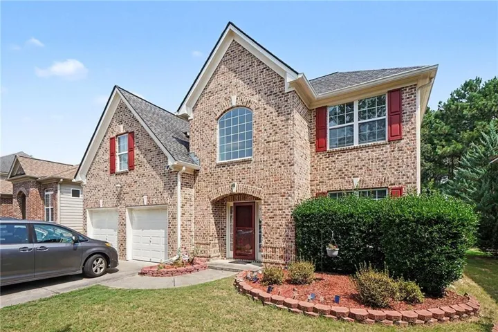 Brick facade two-story residence featuring a prominent arched window and red decorative shutters
