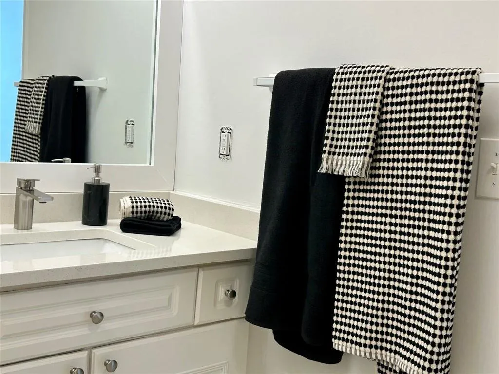 White framed mirror above a light-colored countertop with an undermount sink