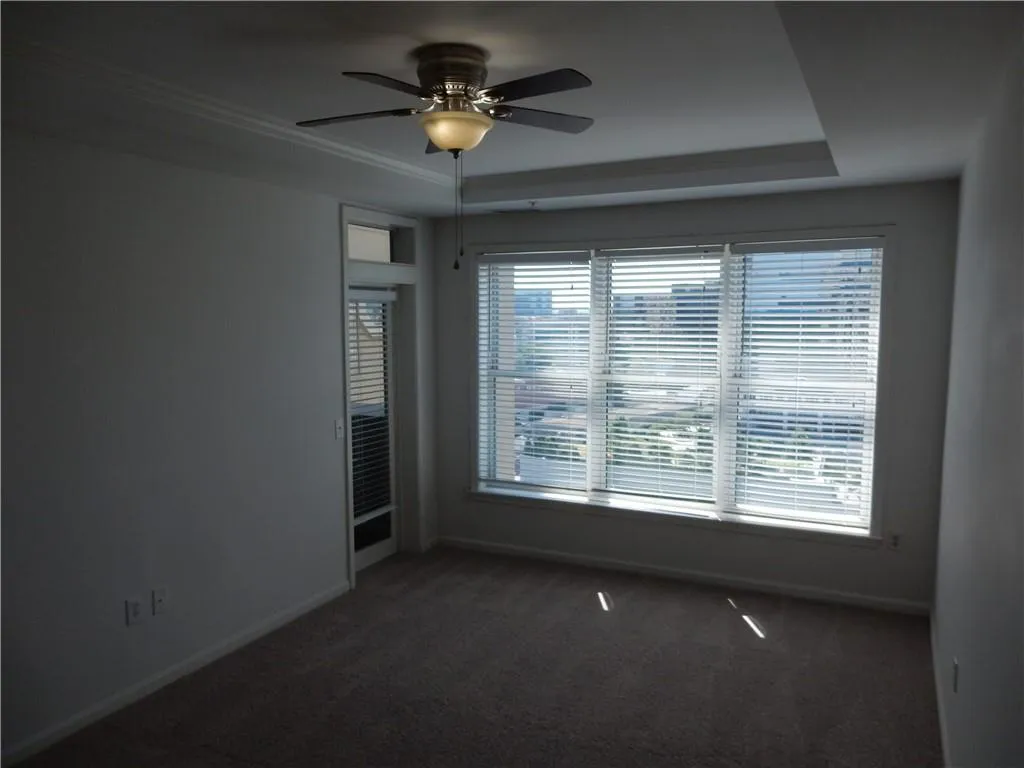 Tray ceiling with crown molding, ceiling fan, carpet flooring, and window blinds