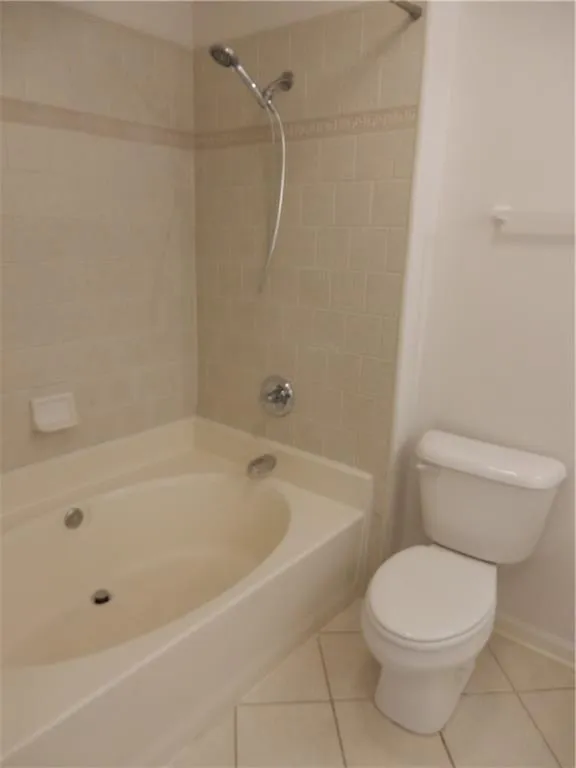 Built-in corner bathtub with integrated shower, wall-mounted showerhead, and tiled surround featuring a decorative accent band