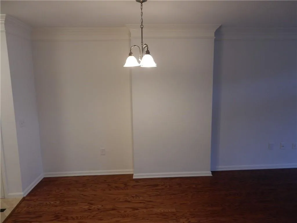 Hardwood flooring, crown molding, and a two-light chandelier illuminate this space