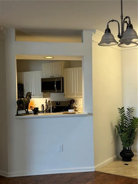 White shaker cabinetry, stainless steel microwave, and recessed lighting