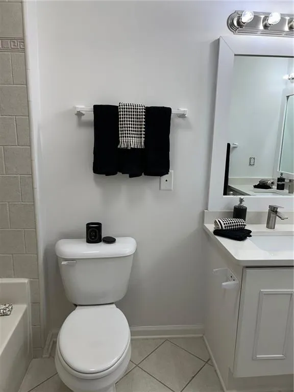 White vanity with a light countertop, under-mount sink, and chrome faucet