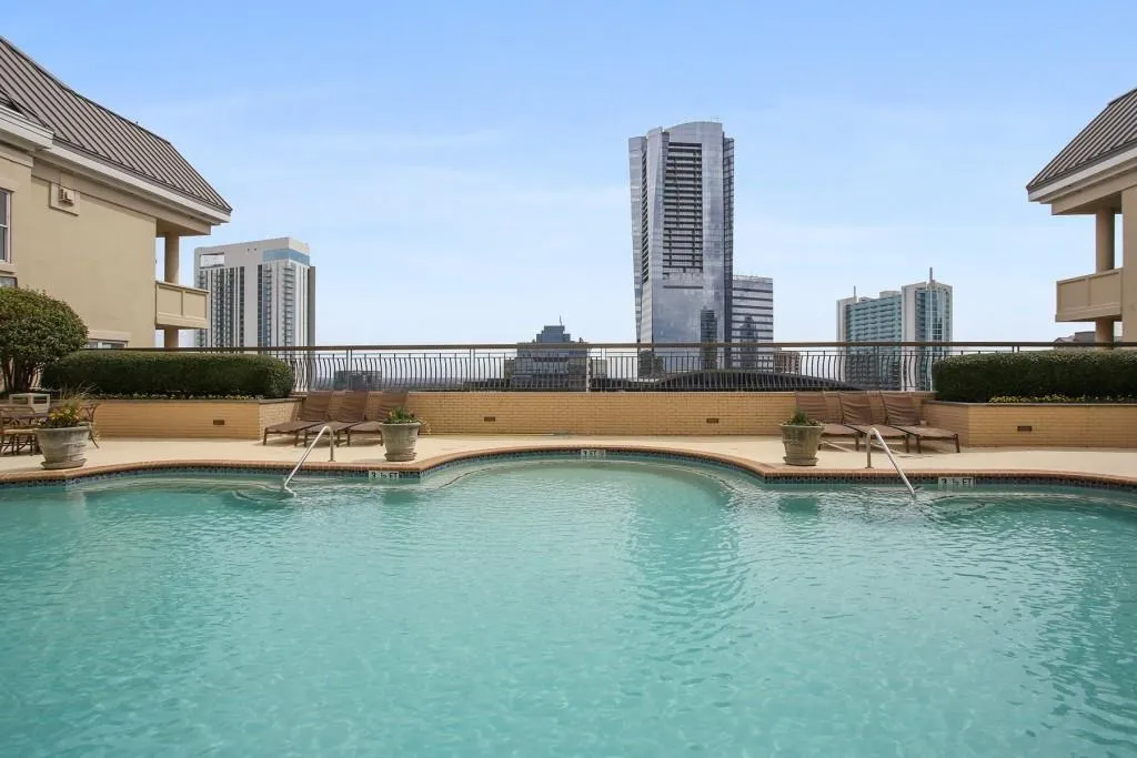 Swimming pool with a curved edge, surrounding concrete decking, and metal handrails