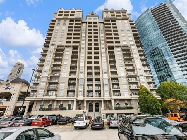 Multi-story building featuring numerous balconies, a columned entrance, and a symmetrical facade